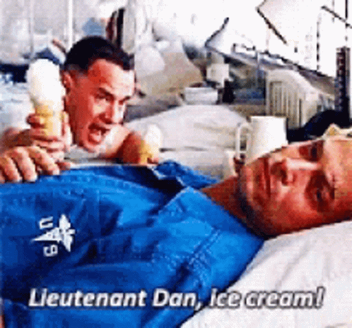 A Man Is Laying In A Hospital Bed While Another Man Holds An Ice Cream Cone In Front Of Him . GIF