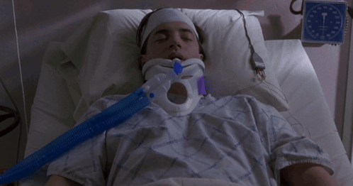A Man Is Laying In A Hospital Bed With A Neck Brace GIF