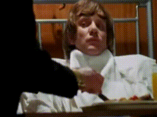 A Man Is Laying In A Hospital Bed With A Tray Of Food GIF