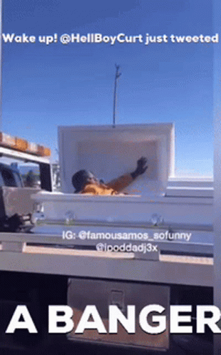 A Man Is Laying In A White Coffin On The Back Of A Truck GIF