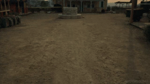 A Man Is Laying In The Dirt In Front Of A Building That Says ' Cowboy ' On It . GIF
