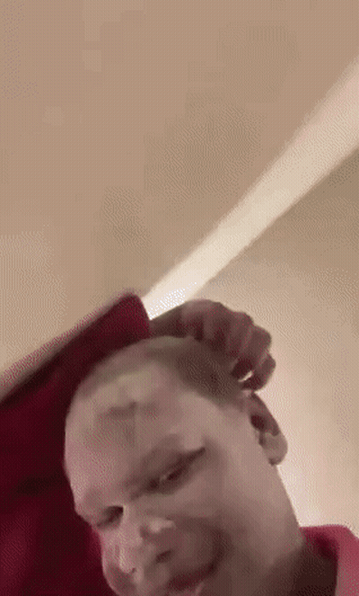 A Man Is Laying On A Bed With A Red Pillow On His Head . GIF