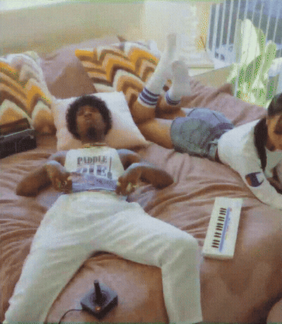 A Man Is Laying On A Bed With A Shirt That Says Puddle On It GIF