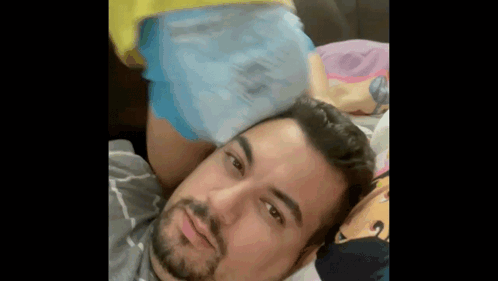 A Man Is Laying On A Bed With A Woman 'S Butt On His Head . GIF