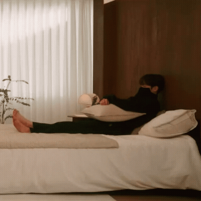 A Man Is Laying On A Bed With His Feet Up GIF