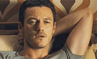 A Man Is Laying On A Bed With His Head On A Pillow . GIF