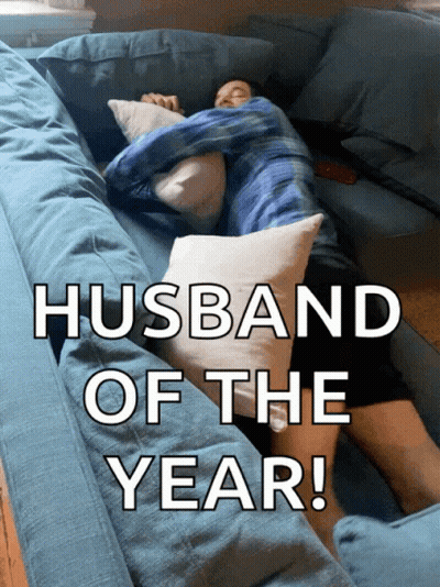 A Man Is Laying On A Blue Couch With The Words Husband Of The Year GIF