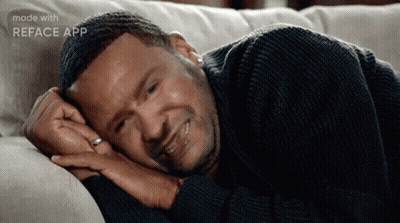 A Man Is Laying On A Couch With His Head On His Hands . GIF