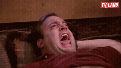 A Man Is Laying On A Couch With His Mouth Open And Laughing . GIF
