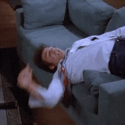 A Man Is Laying On A Couch With His Tie Hanging Off Of Him . GIF