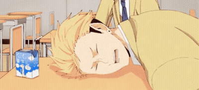 A Man Is Laying On A Desk In A Classroom Next To A Box Of Milk . GIF