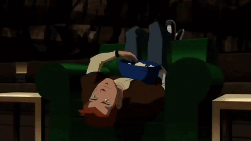 A Man Is Laying On A Green Couch With A Bowl Of Popcorn GIF