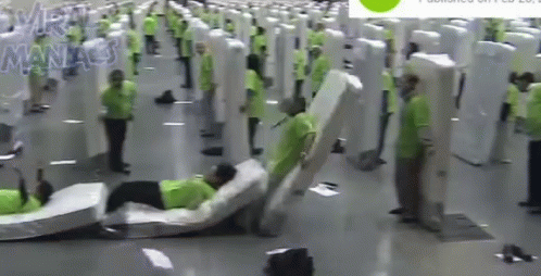 A Man Is Laying On A Mattress In A Room With A Lot Of Mattresses . GIF