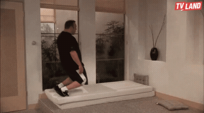 A Man Is Laying On A Mattress In A Room With A Tv Land Logo On The Wall GIF