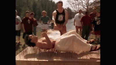 A Man Is Laying On A Mattress Made Of Nails While A Group Of People Watch . GIF