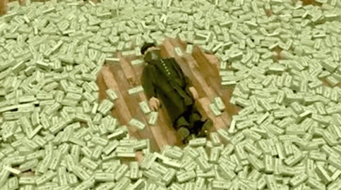 A Man Is Laying On A Pile Of Money On The Floor . GIF