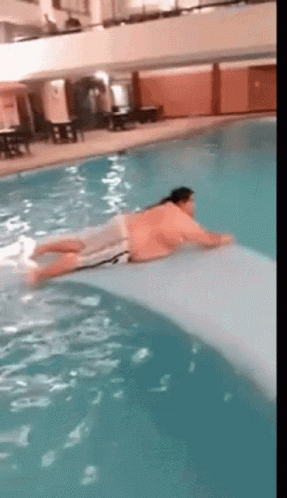 A Man Is Laying On A Raft In A Pool GIF
