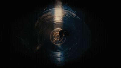 A Man Is Laying On A Record In The Dark . GIF
