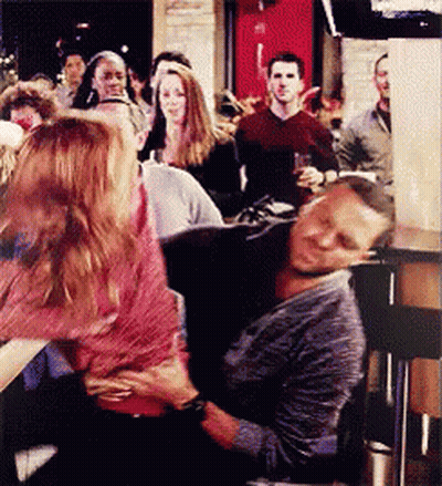 A Man Is Laying On A Woman 'S Lap In A Crowd Of People GIF