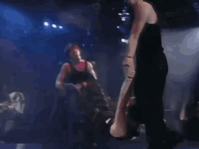 A Man Is Laying On His Back On A Stage While Another Man Stands Behind Him GIF
