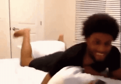 a man is laying on his stomach on a bed with his legs up .
