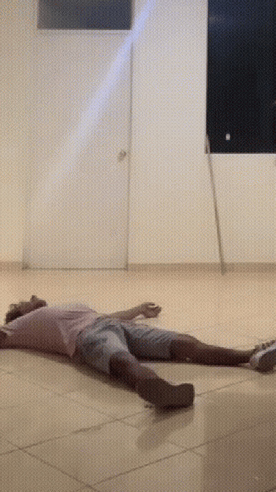 A Man Is Laying On The Floor In A Room With A Mop . GIF