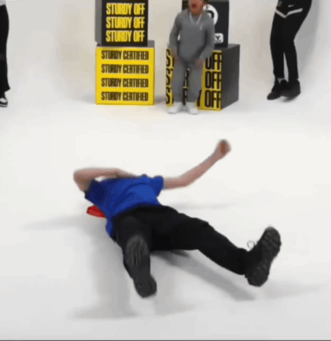 A Man Is Laying On The Floor In Front Of A Yellow Sign That Says Sturdy Off GIF