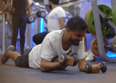 A Man Is Laying On The Floor Lifting Dumbbells GIF