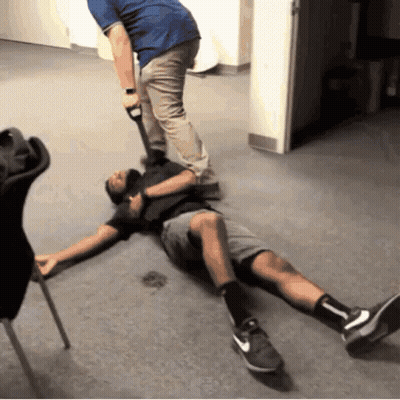 A Man Is Laying On The Floor While Another Man Holds A Hammer GIF