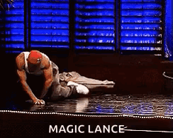 A Man Is Laying On The Floor With A Sign That Says Magic Lance GIF