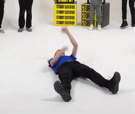 A Man Is Laying On The Floor With A Sign That Says Sturdy Certified GIF
