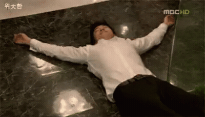 A Man Is Laying On The Floor With His Arms Outstretched GIF