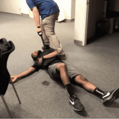 A Man Is Laying On The Floor With His Legs Crossed While Another Man Holds A Shovel . GIF