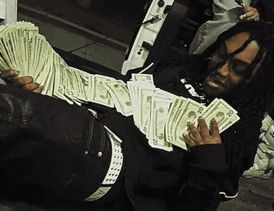 A Man Is Laying On The Ground Holding A Stack Of 20 Dollars GIF