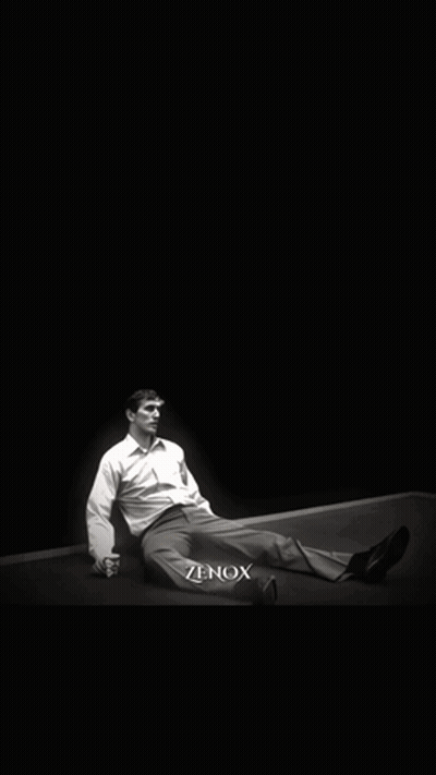 A Man Is Laying On The Ground In Front Of A Large Portrait Of A Man With A Beard And The Word Zenox Below Him GIF