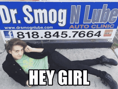 A Man Is Laying On The Ground In Front Of A Sign For Dr. Smog N Lube Auto Clinic GIF