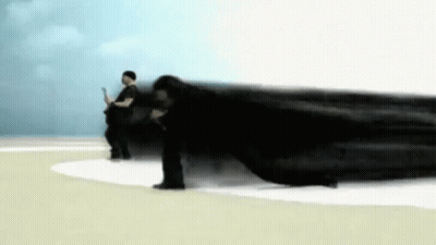 A Man Is Laying On The Ground While Another Man Stands In The Background . GIF