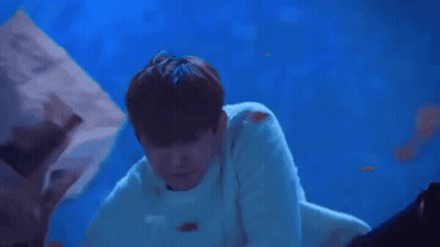 A Man Is Laying On Top Of A Woman In A Blue Water Tank . GIF