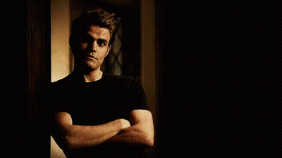 A Man Is Leaning Against A Wall With His Arms Crossed . GIF