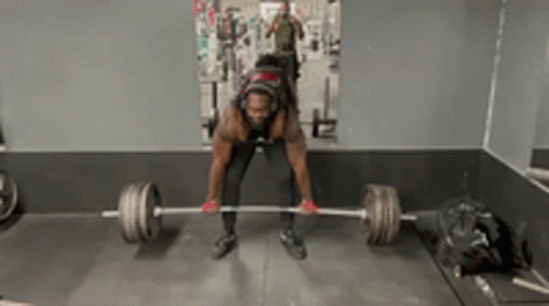 A Man Is Lifting A Barbell In A Gym In Front Of A Mirror GIF