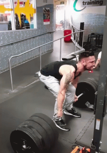 A Man Is Lifting A Barbell In A Gym That Says Training On The Wall GIF