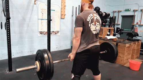 A Man Is Lifting A Barbell In A Gym Wearing A Shirt That Says City Of Death GIF