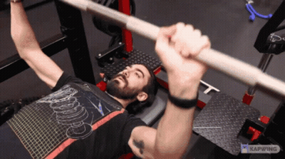 A Man Is Lifting A Barbell While Wearing A Shirt That Says ' Kapwing ' On It GIF
