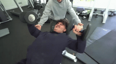 A Man Is Lifting A Dumbbell In A Gym . GIF