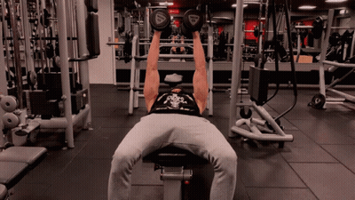 A Man Is Lifting Dumbbells In A Gym With A Reebok Logo On The Dumbbell GIF