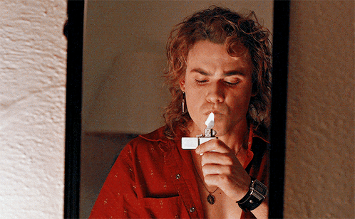 A Man Is Lighting A Lighter In Front Of A Mirror GIF