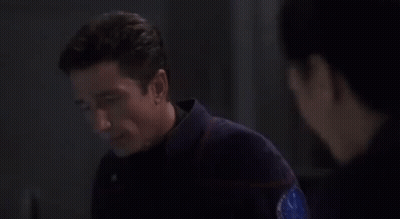 A Man Is Looking At A Woman In A Dark Room . GIF
