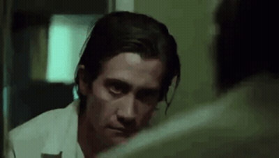 A Man Is Looking At Himself In The Mirror And Making A Funny Face . GIF