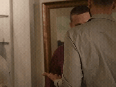 A Man Is Looking At Himself In The Mirror . GIF