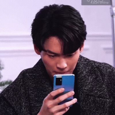 A Man Is Looking At His Cell Phone . GIF